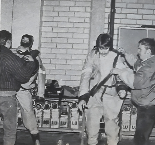 Vaarallisten aineiden torjunnan vaatimiin turvapukuihin sonnustautumassa Luumäen palokuntalaiset Juha Saastamoinen ja Anssi Parkko. Kuva: Luumäen Lehti 10.3.1988.