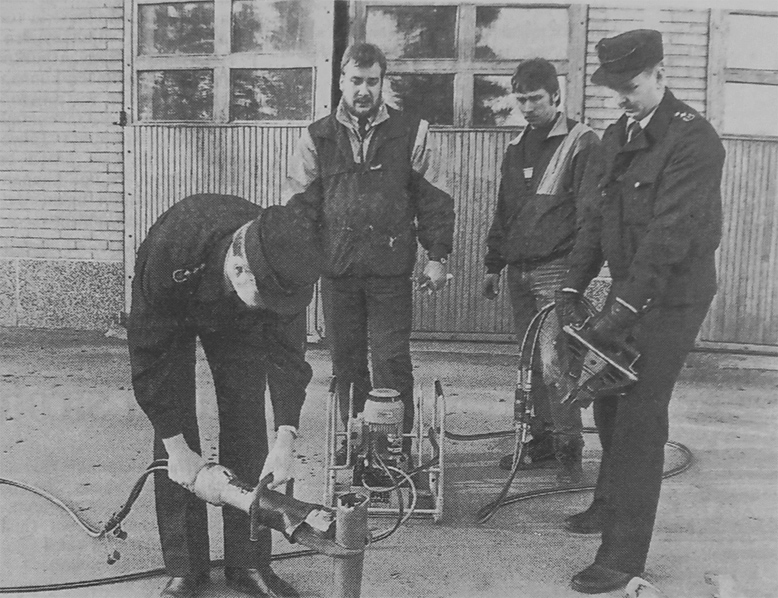 Kuva: Palopäällikkö Lasse Vallentin (vas.), laitteiden toimittajan edustaja Timo Immonen, palomies Jorma Mänttäri ja apulaispalopäällikkö Jari Hyvärinen kokeilivat uusia pelastusvälineitä palokuntaharjoituksen yhteydessä, Kuva: Luumäen Lehti 6.4.1989.